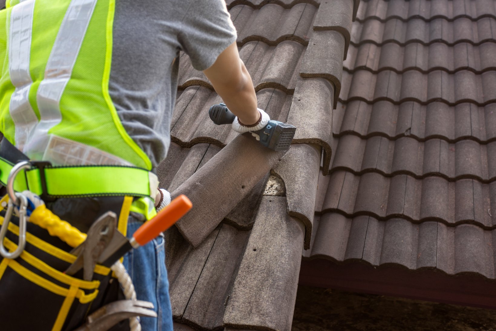 Worker man replace tile of the old roof. Repair roof concept.